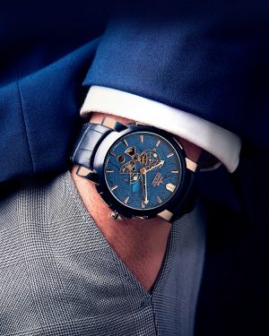 Automatic watch "Meteorit" in blue on the wrist of a gentleman wearing a blue suit and gray trousers.